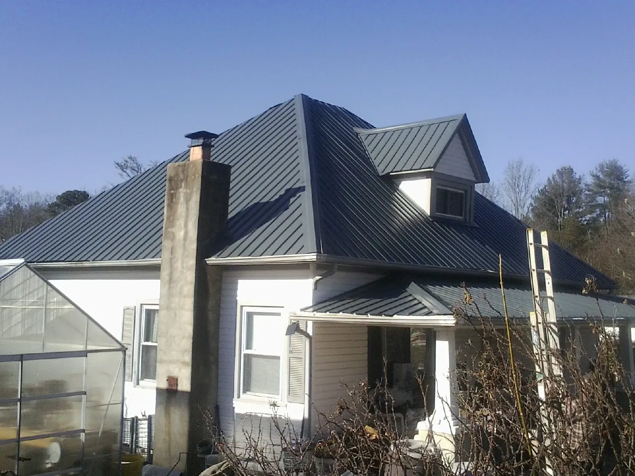 Dark blue standing seam metal roof on a white farmhouse with dormer — Slate & Tile Roof Repair by Roofing Brothers in Draper