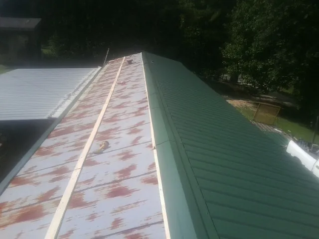 Old rusted panels beside newly installed green metal roofing — Wind Damage Roof Repair by Roofing Brothers in Draper