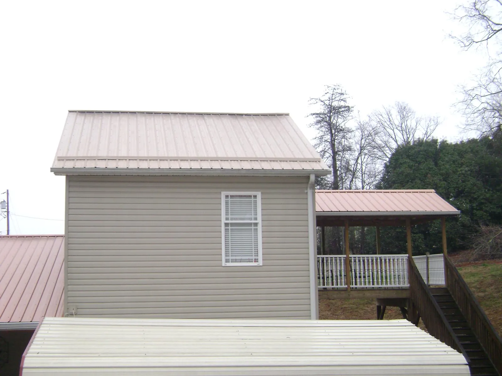 Tan metal roofs on a two story addition and attached porch, from a Roof Replacement job in Draper
